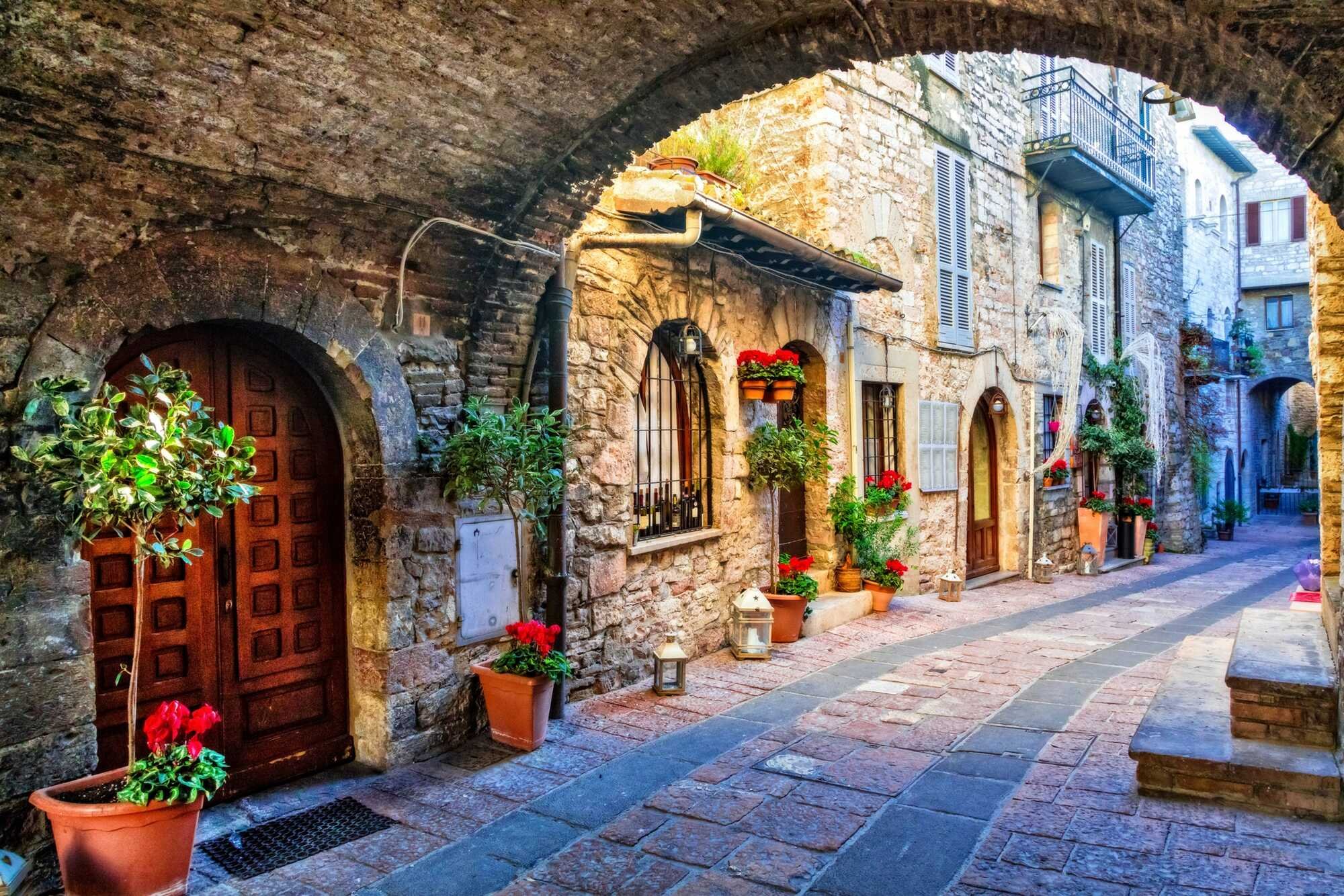 Flower-draped medieval streets of Spello with Renaissance frescoes and stone architecture in Umbria